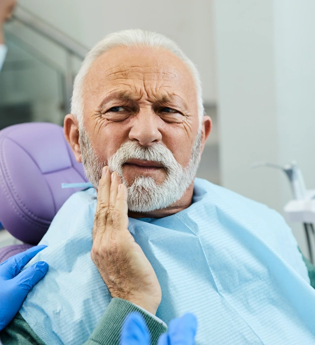 An older man experiencing tooth pain, requiring emergency tooth extraction services in Littleton, CO